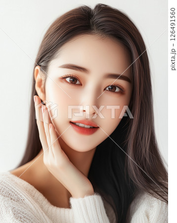 Young Korean woman with long hair posing naturally in soft light setting while gently touching her face 126491560