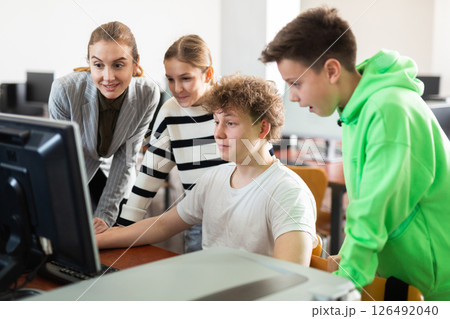 Teenagers studying with female teacher in information technology class 126492040