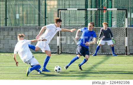 Teens playing soccer football match. Competition between two youth soccer teams Teens playing soccer football match. Competition between two youth soccer teams 126492106