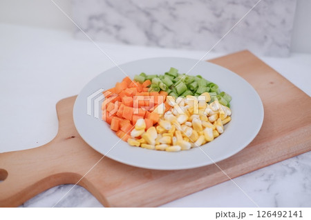 Frozen vegetables on a white plate on a white marble table. 126492141