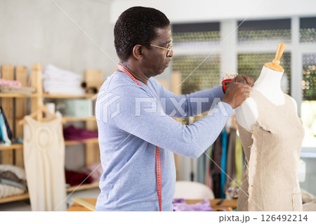 Dressmaker constructing custom dress on mannequin in sewing workshop Dressmaker constructing custom dress on mannequin in sewing workshop 126492214