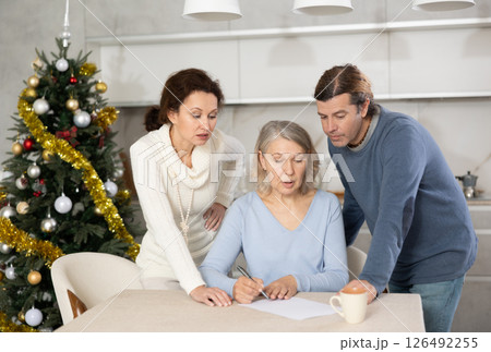 Married couple helps elderly mother write testament in kitchen at christmas 126492255
