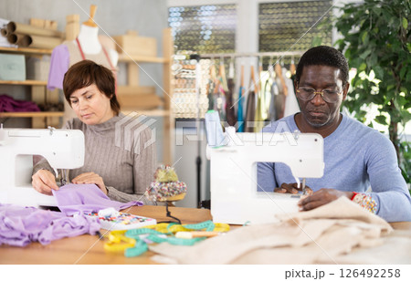 Working in sewing workshop - man and woman working at sewing machines, creating new clothes 126492258
