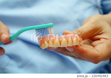Asian senior woman patient clean teeth denture with toothbrush for chew food. Asian senior woman patient clean teeth denture with toothbrush for chew food. 126492463
