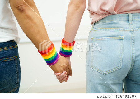 Asian LGBT couple woman holding hand wearing rainbow wristband. Asian LGBT couple woman holding hand wearing rainbow wristband. 126492507