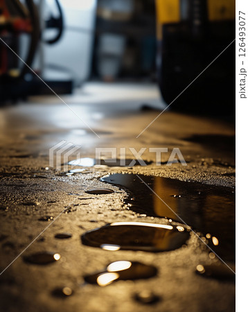 Motor oil change captured from floor level highlighting the reflections and details on the garage floor 126493077