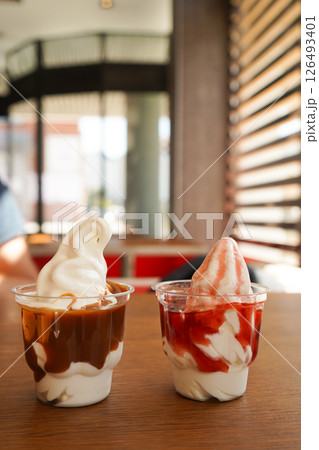 Two plastic cups with strawberry and caramel ice cream. 126493401