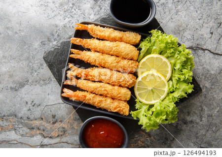 Tempura deep-fried EBI prawns with spiced sauces closeup on plate. Horizontal top view 126494193