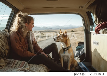 Woman and Dog Enjoying Scenic View from Van in Mountain Landscape During Golden Hour 126494861