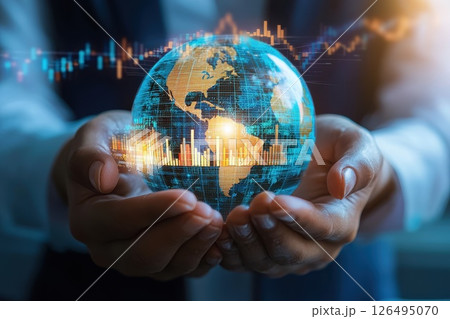 A person is holding a globe with a computer screen behind it 126495070