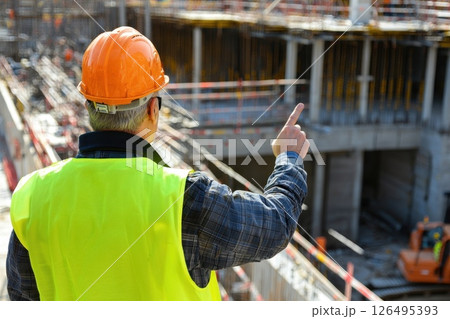 Construction Safety Officer in Neon Vest Signals with Determined Expression at Site 126495393