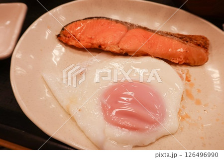 Close up of a Japanese style breakfast grilled salmon and pan fried sunny side up egg on a white plate  126496990