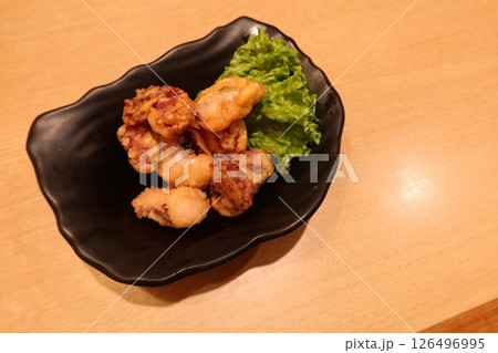close up of Japanese small pieces of deep fried squid snacks on a black plate with copy space close up of Japanese small pieces of deep fried squid snacks on a black plate with copy space 126496995