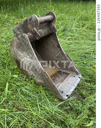 Large, rusty metal bucket is sitting on the grass Large, rusty metal bucket is sitting on the grass 126497393