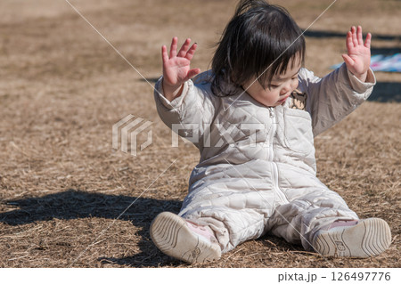 【相模原市立麻溝公園の芝生広場で遊ぶ1歳児　座る】 126497776