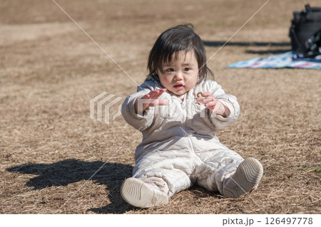 【相模原市立麻溝公園の芝生広場で遊ぶ1歳児　座る】 126497778