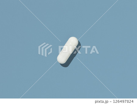 White Medical capsule on blue top view, hard shadows. Taking dietary supplements 126497824