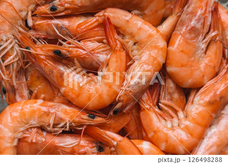 Close-up of a pile of fresh, cooked shrimp with vibrant orange shells and detailed textures 126498288