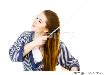Woman brushing her long hair using comb Woman brushing her long hair using comb 126499575