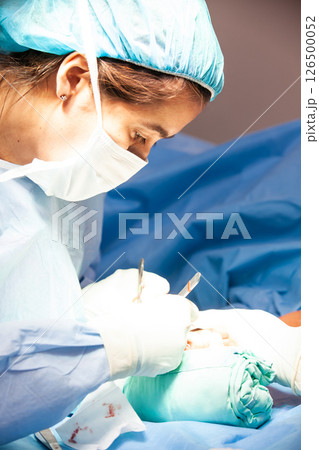 Female doctor performing a surgery. Orthopedic surgeon. Surgery and insurance concept. 126500052