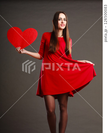 Woman in red dress holds heart sign 126500083