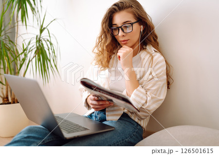 Cute woman using laptop while sitting on floor at home. Remote work from home. Freelancing concept. Cute woman using laptop while sitting on floor at home. Remote work from home. Freelancing concept. 126501615