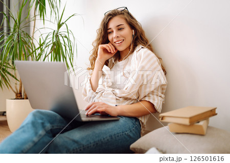 Cute woman using laptop while sitting on floor at home. Remote work from home. Freelancing concept. Cute woman using laptop while sitting on floor at home. Remote work from home. Freelancing concept. 126501616