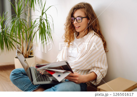 Cute woman using laptop while sitting on floor at home. Remote work from home. Freelancing concept. 126501617