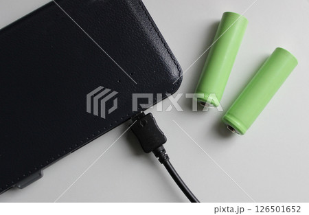 Portable Power Energy Sources. Rechargeable Batteries Near Charged Power Bank Isolated On White Top View Portable Power Energy Sources. Rechargeable Batteries Near Charged Power Bank Isolated On White Top View 126501652