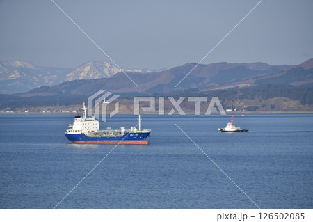 春の北海道函館市で函館湾に停泊中の貨物船とクルーズ船を迎えに行くタグボートの風景を撮影 126502085