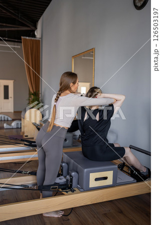 Woman doing rotation exercise on Pilates Reformer for the chest and back muscles, focusing on flexibility, strength, and control with determination 126503197