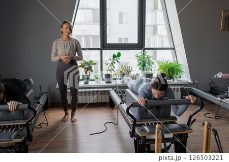 Woman training pilates on the reformer bed. Reformer pilates studio machine for fitness workouts in gym. Fit, healthy and strong authentical body. Fitness concept 126503221