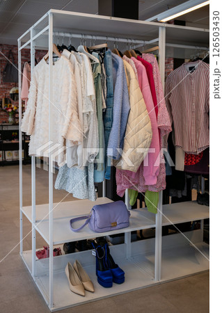women's summer clothing in various colors and fabrics hanging on hangers in thrift shop. Second hand women's summer clothing in various colors and fabrics hanging on hangers in thrift shop. Second hand 126503430