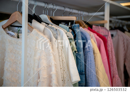 women's summer clothing in various colors and fabrics hanging on hangers in thrift shop. Second hand 126503532