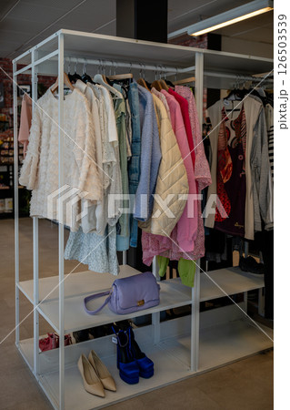 women's summer clothing in various colors and fabrics hanging on hangers in thrift shop. Second hand 126503539