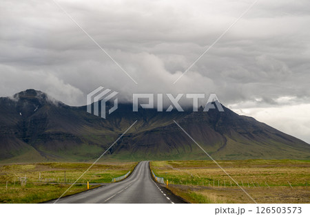 Empty road leading to misty mountain range under dramatic cloudy sky in Iceland Empty road leading to misty mountain range under dramatic cloudy sky in Iceland 126503573
