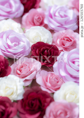 ピンクの背景に並べられた色とりどりの造花のバラ 126503760