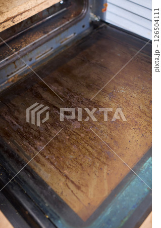 Interior of a dirty oven displaying baked on grease and unsightly stains throughout it Interior of a dirty oven displaying baked on grease and unsightly stains throughout it 126504111