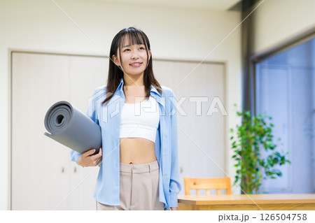 ヨガマットを持つお腹を出した私服の若い女性　ヨガ　ストレッチ　ダイエット　健康 126504758
