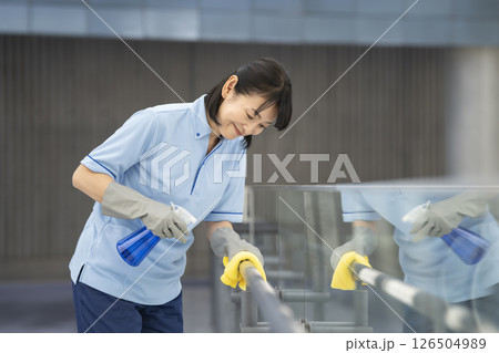 ビル清掃イメージ　通路の手すりを拭く50代の女性清掃スタッフ 126504989