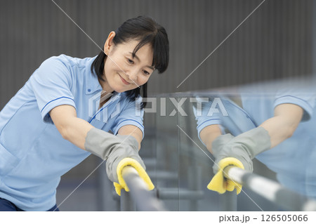 ビル清掃イメージ　通路の手すりを拭く50代の女性清掃スタッフ 126505066