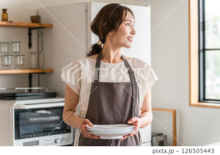 キッチンで家事をするエプロン姿の若いアジア人女性 キッチンで家事をするエプロン姿の若いアジア人女性 126505443