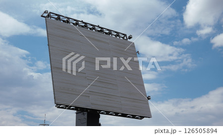 A large digital billboard looms over a war-torn area, emphasizing the contrast between modern technology and the impact of ongoing conflict on daily life A large digital billboard looms over a war-torn area, emphasizing the contrast between modern technology and the impact of ongoing conflict on daily life 126505894