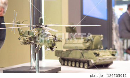 Model helicopter and armored vehicle represent military technology at a defense exhibition, highlighting advancements in warfare capabilities and strategies. Model helicopter and armored vehicle represent military technology at a defense exhibition, highlighting advancements in warfare capabilities and strategies. 126505911