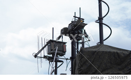 Military personnel operate advanced communication equipment atop a tower in a conflict area, enhancing coordination and tactical responses during wartime operations. 126505975