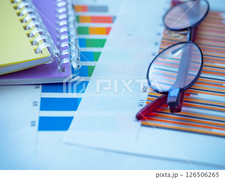 テーブルに置かれたグラフと手帳とメガネ 126506265