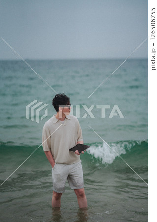 リゾート地の海岸でタブレットで仕事をする男性 126506755
