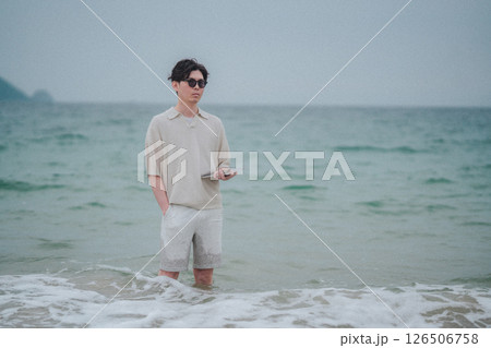 リゾート地の海岸でタブレットで仕事をする男性 リゾート地の海岸でタブレットで仕事をする男性 126506758