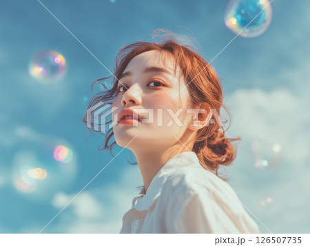 青空とシャボン玉に包まれた女性の横顔 126507735