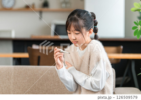 体調不良で体温計で検温する小学生,中学生の女の子 126509579